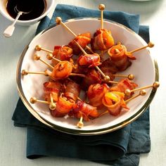 bacon wrapped in toothpicks on a white plate next to a cup of coffee