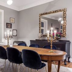 a dining room table with blue chairs and a large mirror on the wall above it