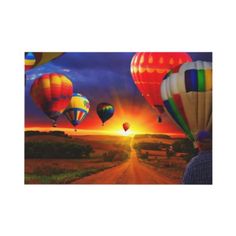 three hot air balloons flying in the sky over a dirt road with a sunset behind them