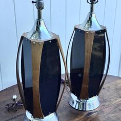 two large metal vases sitting on top of a wooden table next to each other