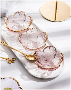 three pink and gold dishes on a white tray