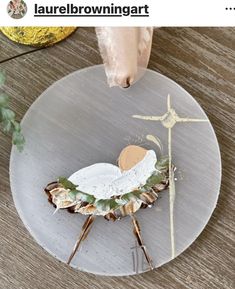 a white plate topped with a baby jesus in a manger surrounded by seashells