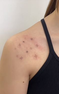 a woman's back with small stars on her left shoulder and chest tattoo design