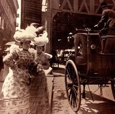 black and white photograph of two women standing next to a horse drawn carriage