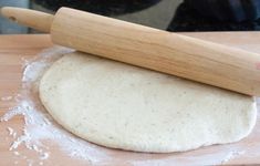 a wooden rolling pin sitting on top of a table next to a floured dough