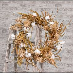 a wreath made out of cotton on top of an old wooden steplade in front of a brick wall