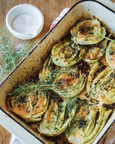 a casserole dish filled with artichokes and topped with dill