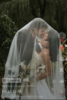 a bride and groom kissing under a veil