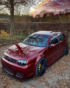 a red car parked on top of a dirt road