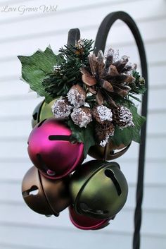 a christmas ornament hanging from a pole with pine cones and berries on it