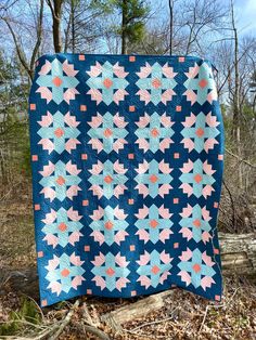 a blue and pink quilt sitting in the woods