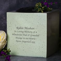 a memorial block with flowers and a rose on the side, in front of it