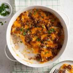 a casserole dish with meat and cheese on top, next to a fork