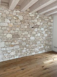 an empty room with wood flooring and stone wall