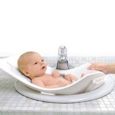 a baby sitting in a bath tub next to a faucet