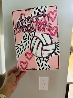 a hand holding up a pink and black volleyball card