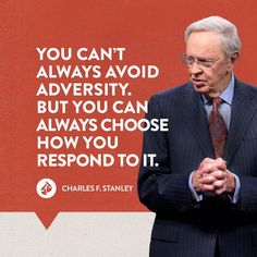 a man in a suit and tie standing next to a red wall with a quote on it