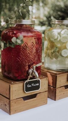 three jars with flowers in them sitting on top of wooden crates at an outdoor wedding