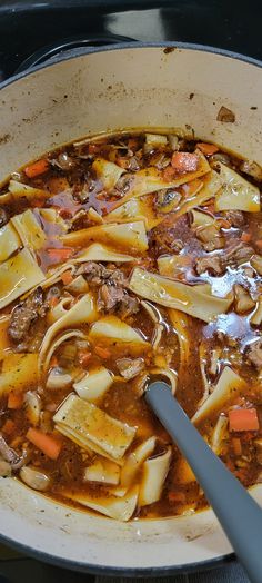 a large pot filled with soup on top of a stove next to a spatula