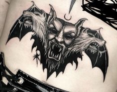 a woman's stomach with tattoos on it and two demon heads in the middle