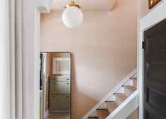 a hallway with stairs and a mirror on the wall next to an open door that leads to another room