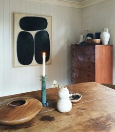 a wooden table with a candle on top of it next to a vase and other items