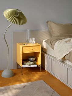 a yellow nightstand next to a white bed