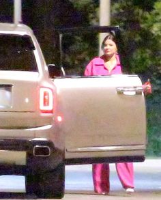 a woman in pink is standing next to a silver truck with the back door open