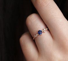 a woman's hand with a diamond and blue sapphire ring on her left finger