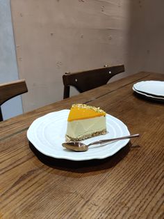 a piece of cheesecake on a white plate with a fork and two empty plates