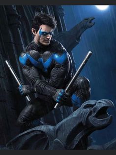 a man in blue and black costume holding two bats