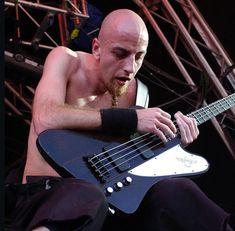 a shirtless man playing an electric guitar on stage