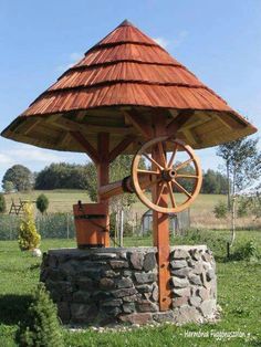 a wooden structure with a water wheel on it's side in the middle of a field