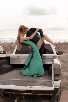 a woman in a green dress sitting on the back of a pickup truck