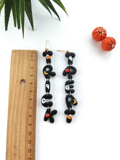 two pairs of black and orange beaded earrings next to a ruler with an orange plant in the background