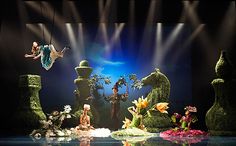 the stage is decorated with fake flowers and fairy figurines, including a man on a swing