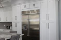 a kitchen with white cabinets and stainless steel refrigerator