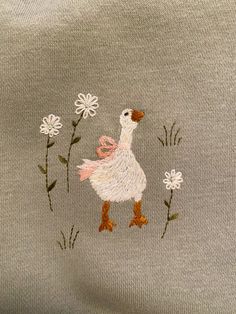 an embroidered sweater with a duck and daisies on the front, along with white flowers