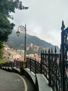 an iron fence next to a street light with a city view in the back ground