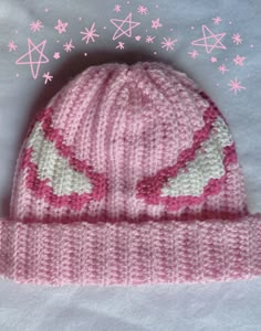 a pink knitted hat sitting on top of a white blanket next to snowflakes