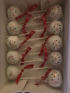 there are many snowmen in the box with red ribbon around them and on sticks