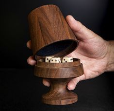 a person holding a wooden object with dice in it