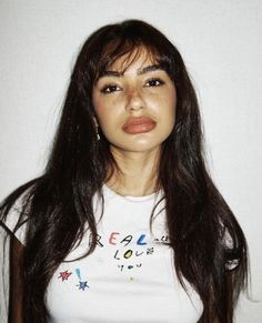 a woman with long brown hair wearing a white shirt