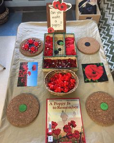 a table topped with lots of red flowers and books on top of a white table cloth