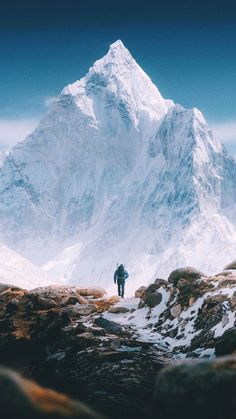 a man standing on top of a snow covered mountain next to a tall white peak