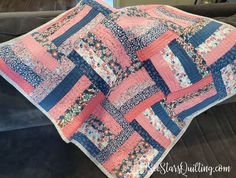 a pink and blue quilt sitting on top of a couch