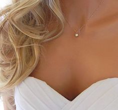 a woman wearing a white dress with a gold necklace on her neck and the back of her head