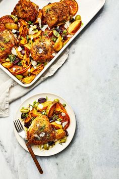 two plates with chicken and vegetables on them next to a baking pan full of food