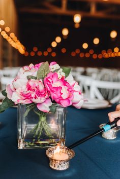 a vase filled with pink flowers sitting on top of a blue table covered in lights