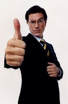 a man in a suit and tie giving the thumbs up sign with his right hand